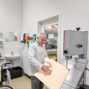 Ein Mitarbeiter von Hodey arbeitet an einer orthopädischen Schaumstoffschicht in einer Werkstatt.